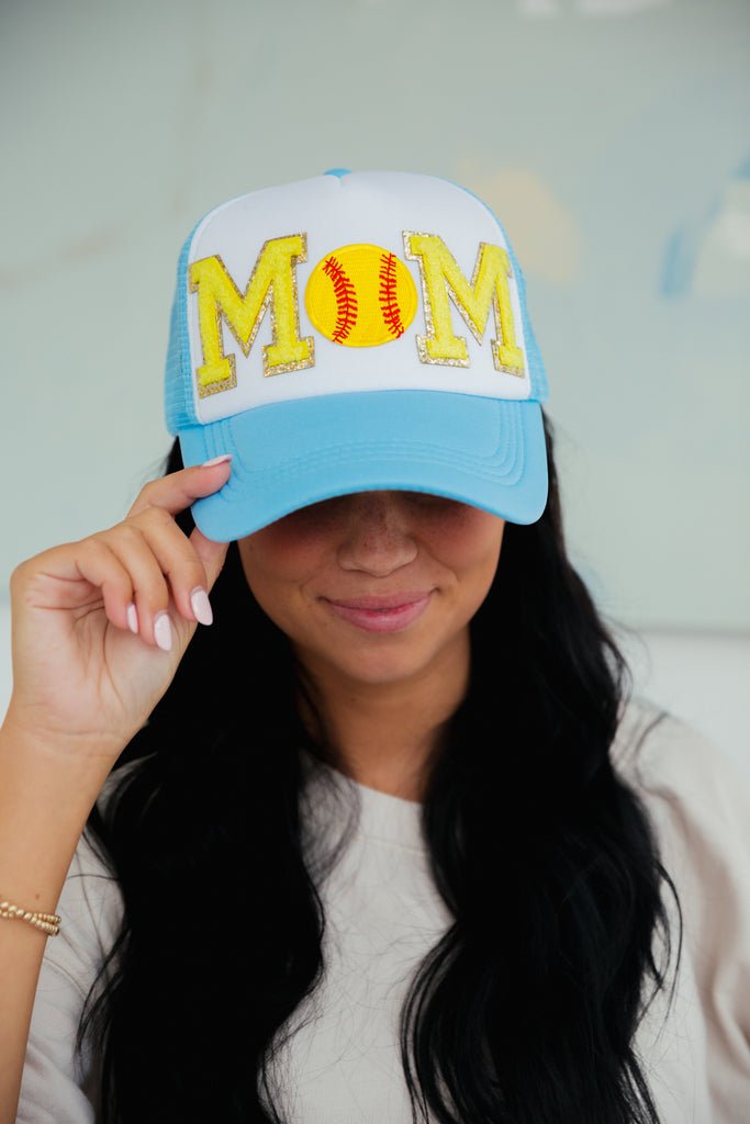 White and blue trucker hat with Mom in mini yellow glam letters and a softball patch
