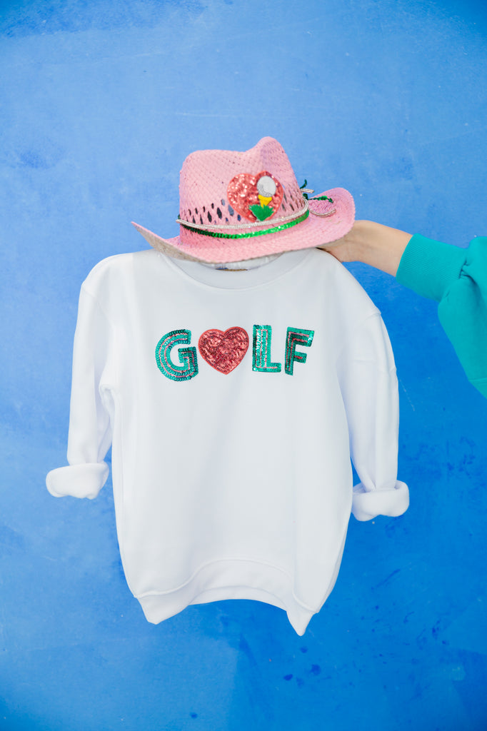 Kids white pullover with "golf" in green sequin lettering and a red sequin heart patch.  