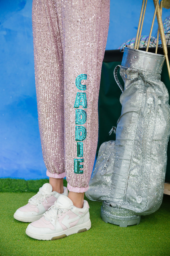 Sequin joggers with "caddie" in blue sequin lettering down the left leg. 