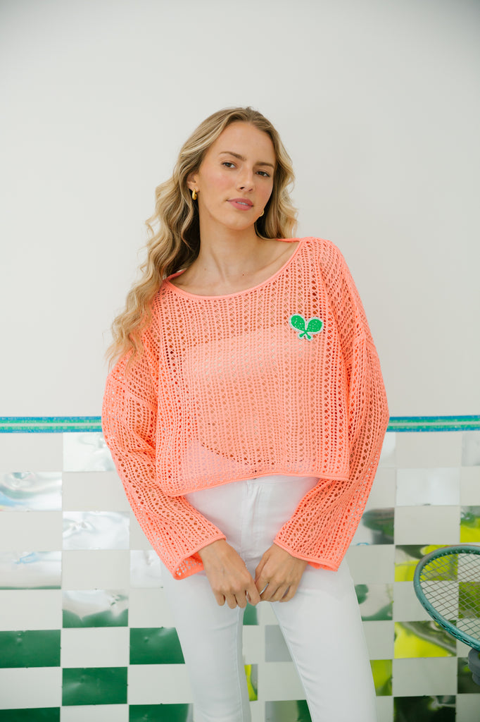 Coral crochet sweater with green tennis racket patch. 