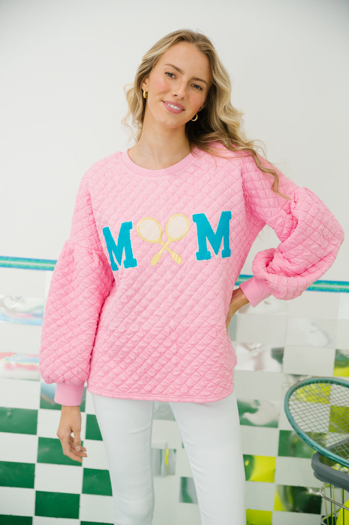 Pink quilted pullover with "mom" in blue varsity letters and a gold tennis racket patch. 