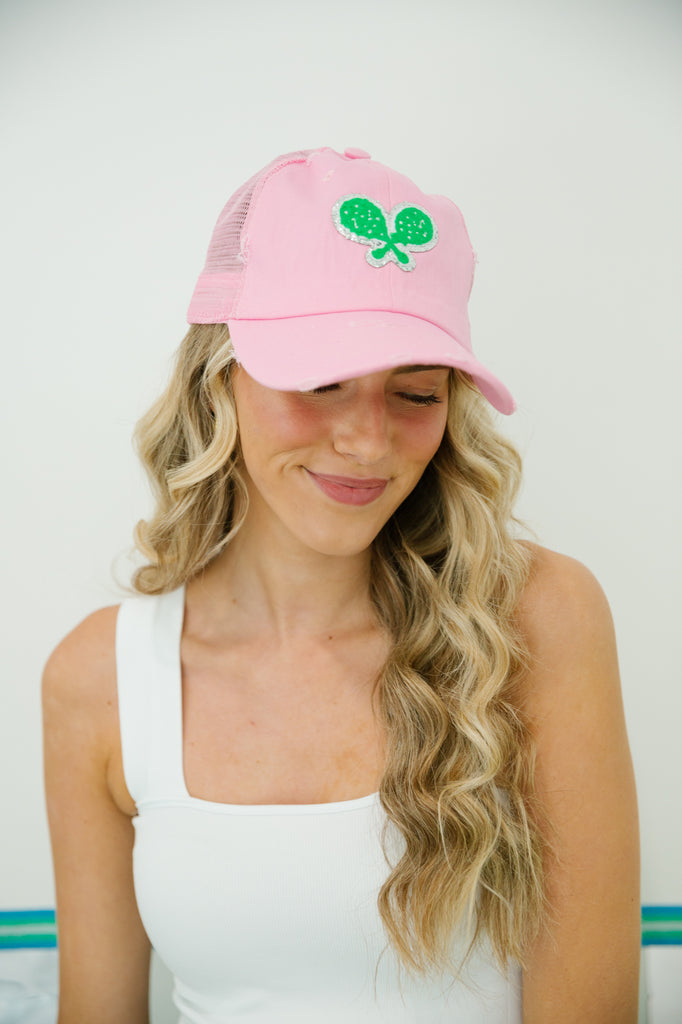 Light pink hat with green tennis racket patch. 