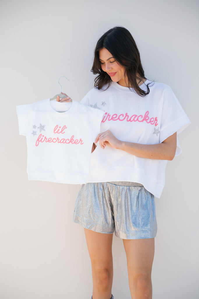 Kids white top with "Lil Firecracker" printed in pink with silver stars.  
