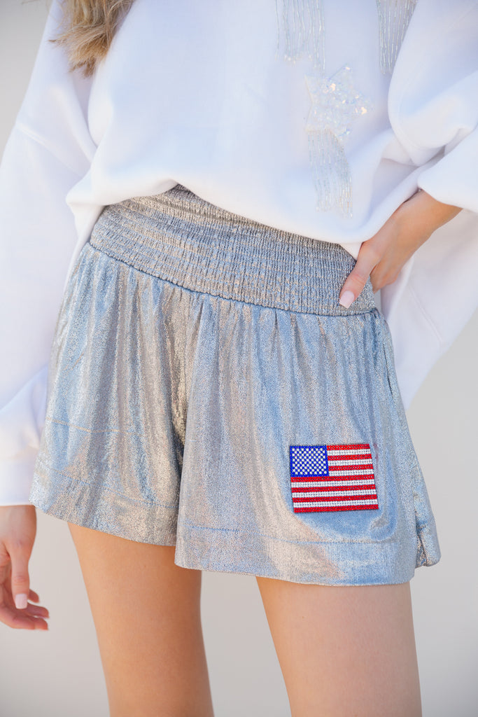 Silver flowy shorts with an American flag patch