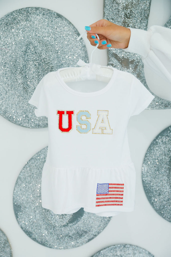Kids white top with red, white, and blue "USA" letters and an American flag patch