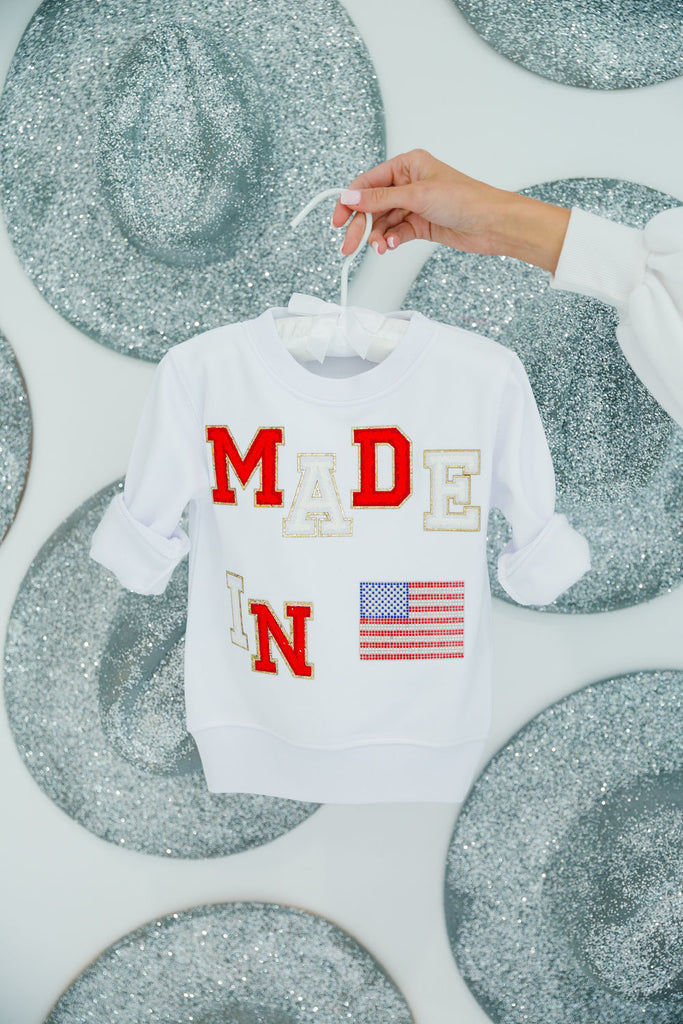 Kids white pullover with "Made In" in red and white letters with an American flag patch