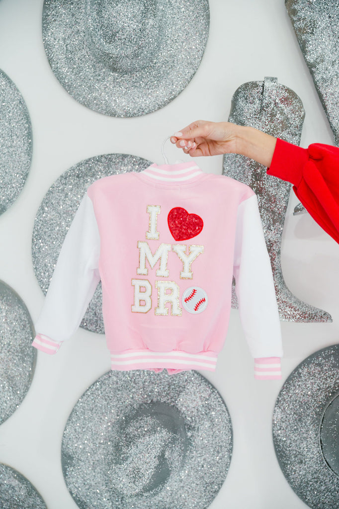 Kids pink and white varsity jacket with "I Heart My Bro" in white letters with a red heart patch and a baseball patch as the "O"