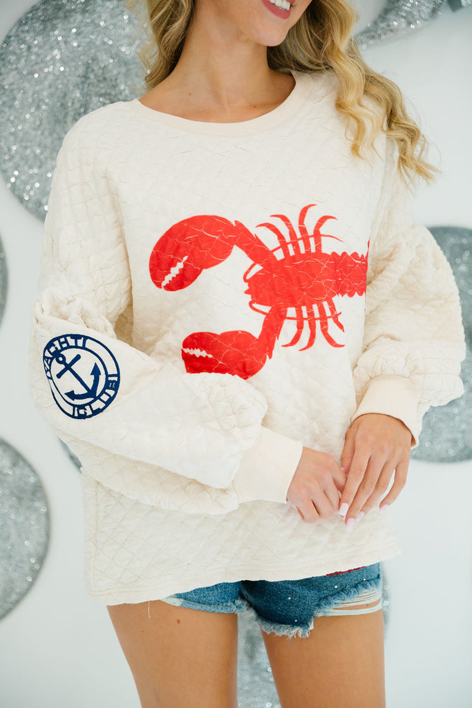 Cream quilted long pullover with a red lobster print and navy yacht club patch on the sleeve