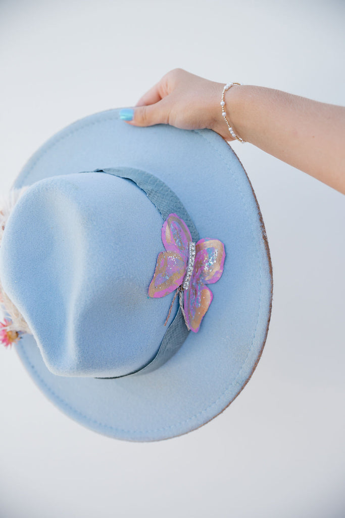 Baby blue rancher hat with pastel butterfly patch and flower band with feathers. 