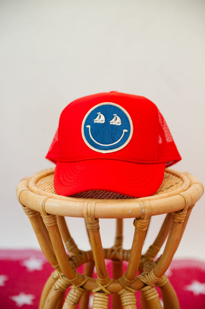 Kids red trucker hat with a sailboat smiley face patch