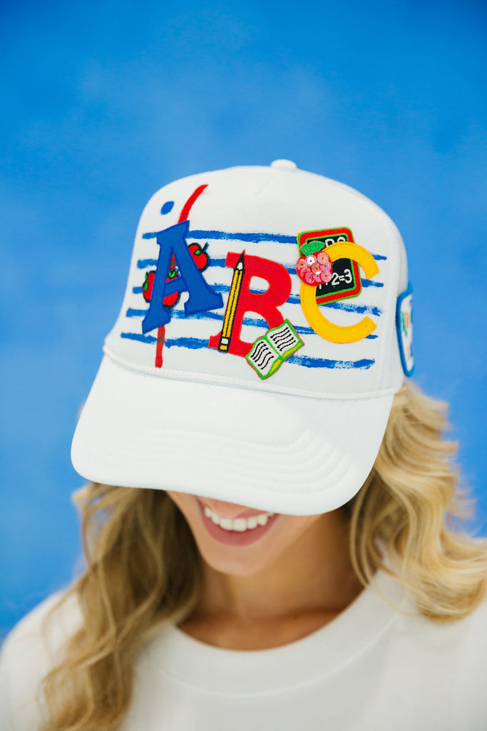 White trucker hat with blue stripes and ABC's patch