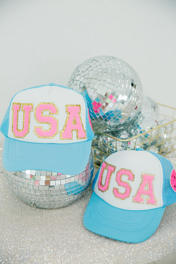 Kids white and blue trucker hat with pink "USA" letters and smiley face