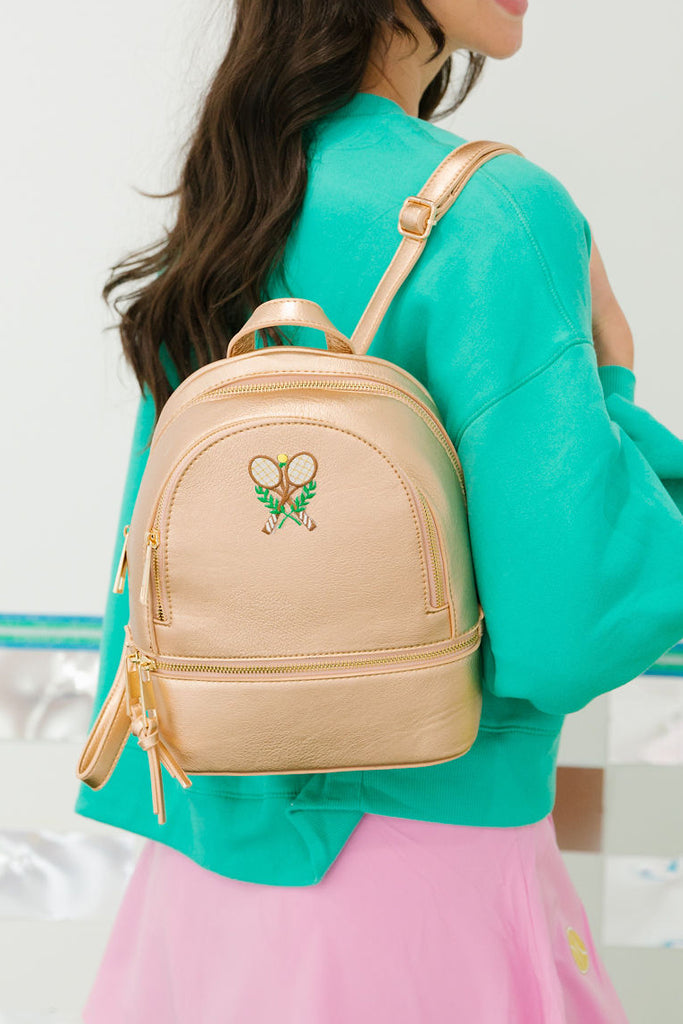 Gold small leather backpack with a tennis racket patch
