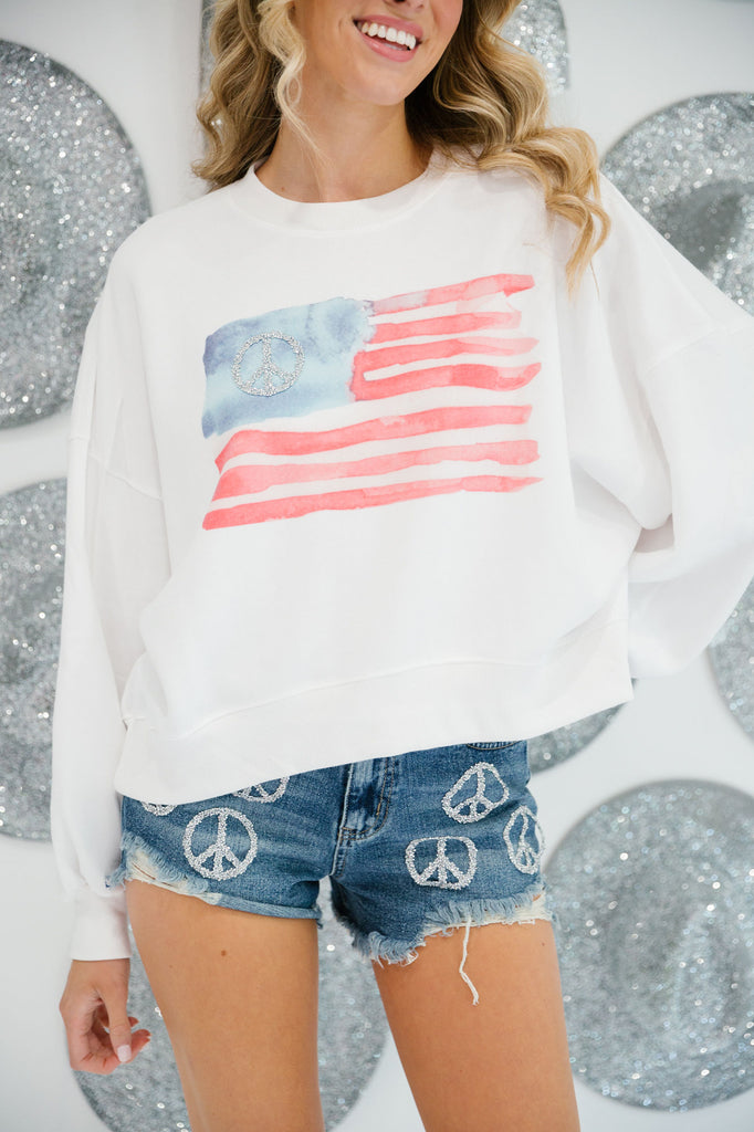 White cropped pullover with a watercolor American flag print and a silver peace sign