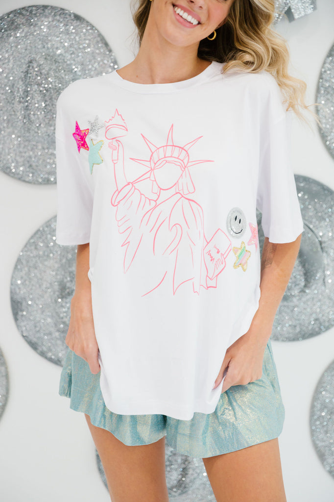White t-shirt with a pink outlined Lady Liberty print with star and smiley face patches