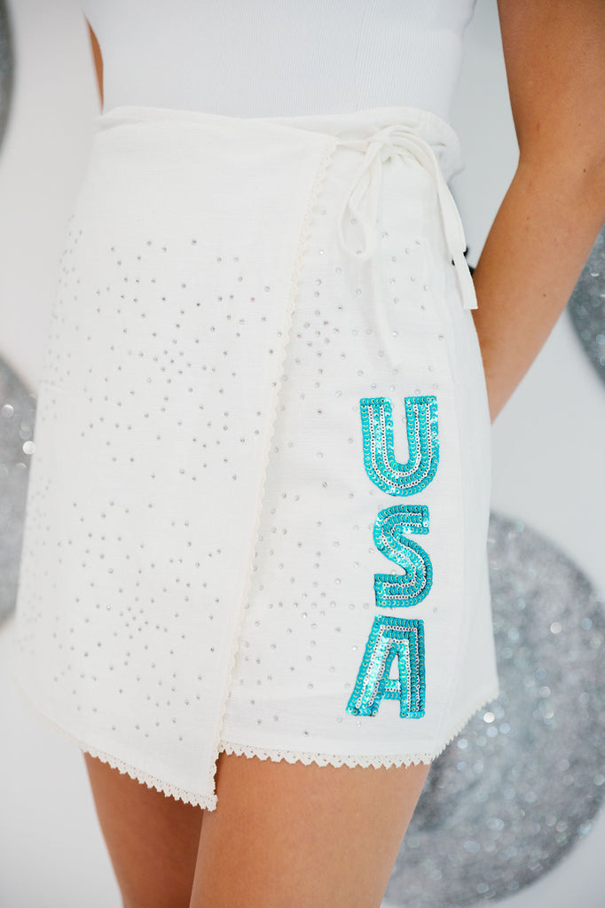 White wrap skirt with silver rhinestones and blue sequin "USA" letters going down the front side