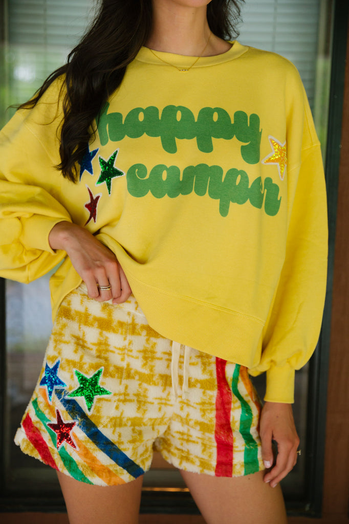 Yellow cropped pullover with "happy camper" in green printed lettering and sequin star patches. 