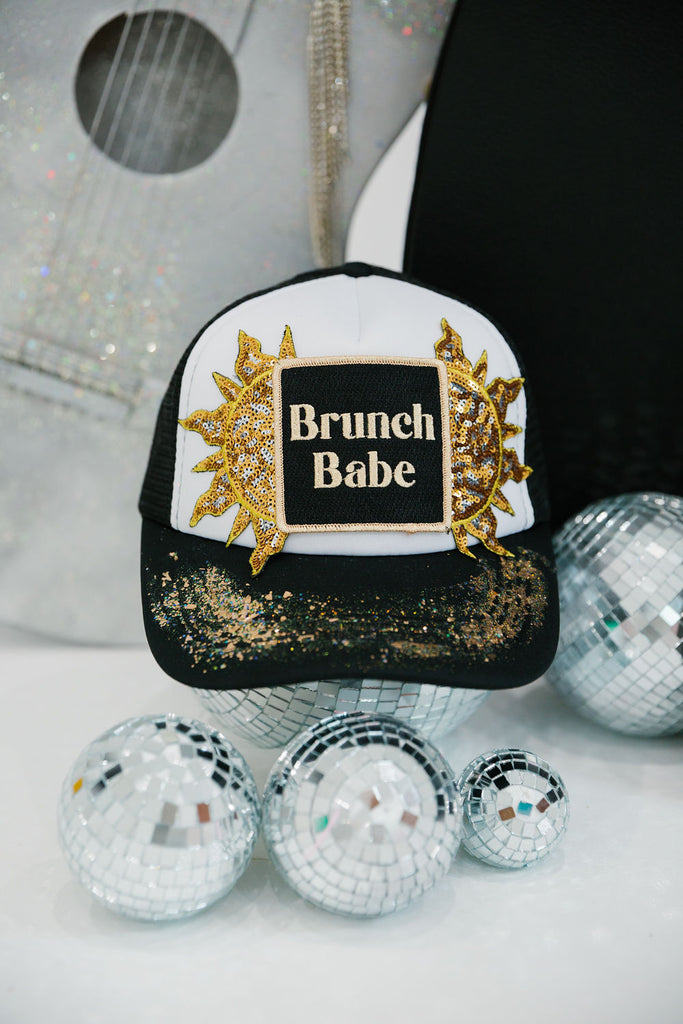 Black and white trucker hat with Brunch Babe patch, sun patches, and gold glitter