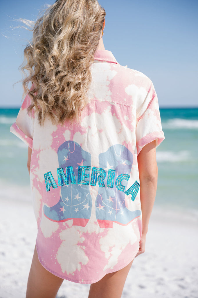 Pink tie dye short-sleeve button down with cowboy boots print across the back with "America" in blue sequin letters