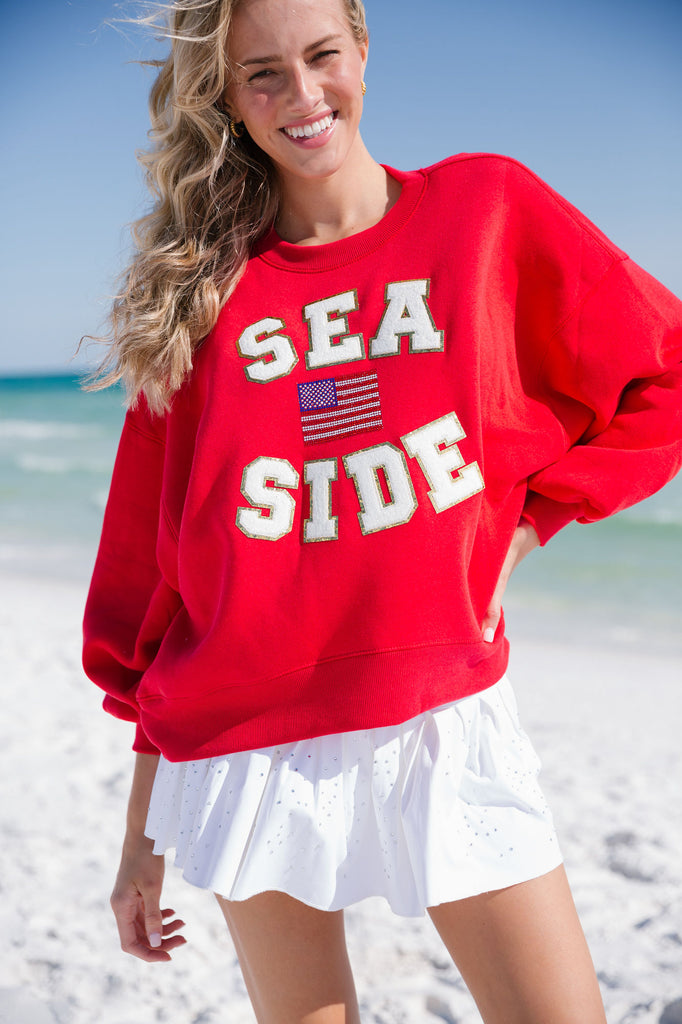 Red cropped pullover with "Sea Side" in white letters and American flag patch