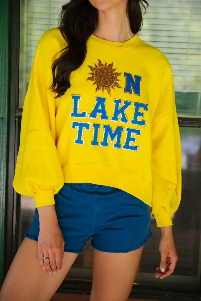 Yellow cropped pullover with "on like time" in blue terry lettering and sequin sun patch. 
