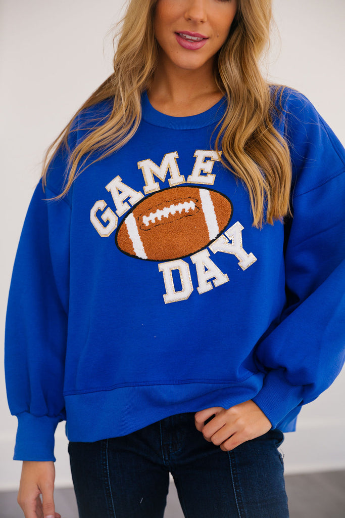Royal blue pullover with "game day" in mini white glam lettering with football patch. 