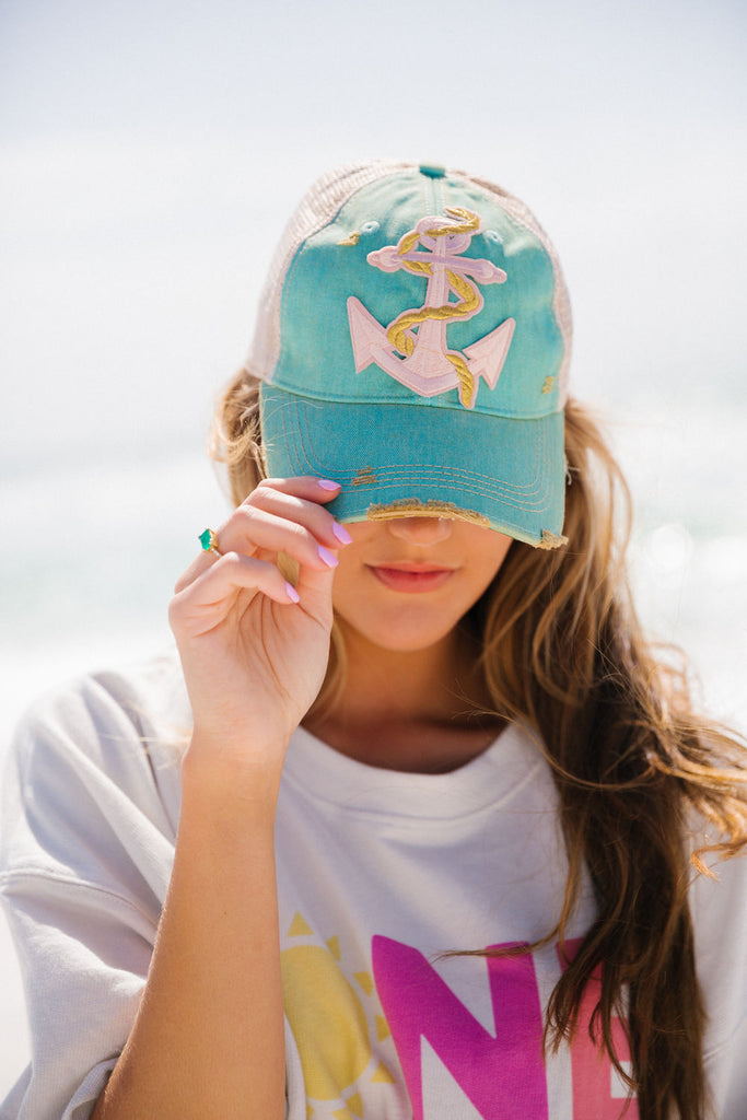 Teal distressed baseball hat with a pink anchor patch