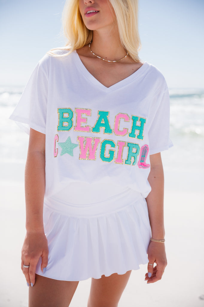 White t-shirt with Beach Cowgirl in alternating turquoise and light pink terry letters with a star and cowboy boot patch
