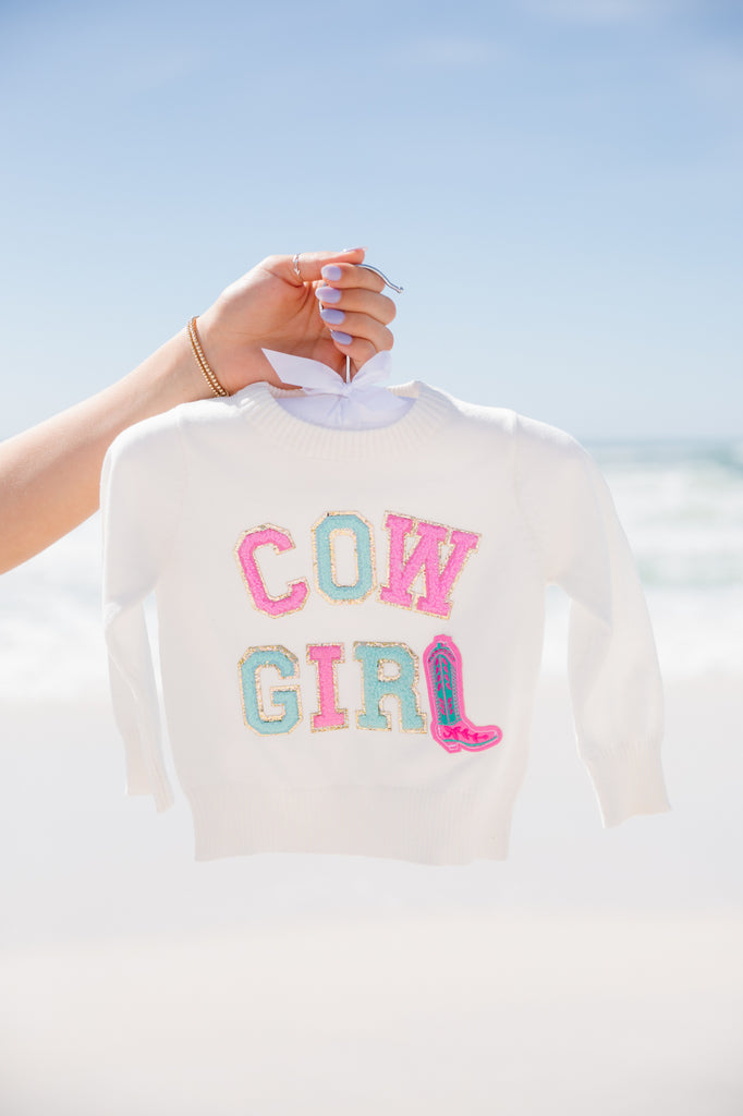 Kids white sweater with "cowgirl" in mini pink and teal terry letters alternating with a pink cowboy boot. 