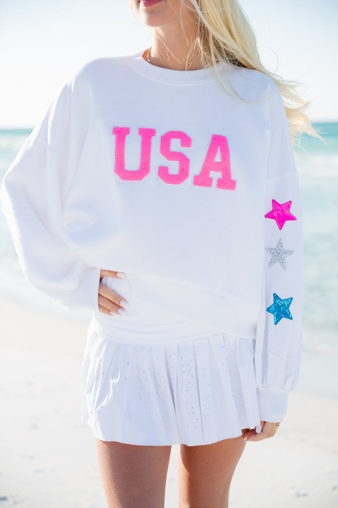 White cropped pullover with pink "USA" letters and stars on the sleeve
