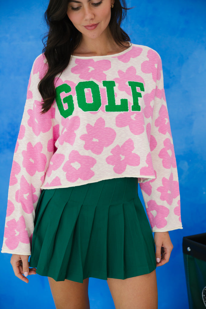 Pink and white floral sweater with "golf" in green varsity lettering. 