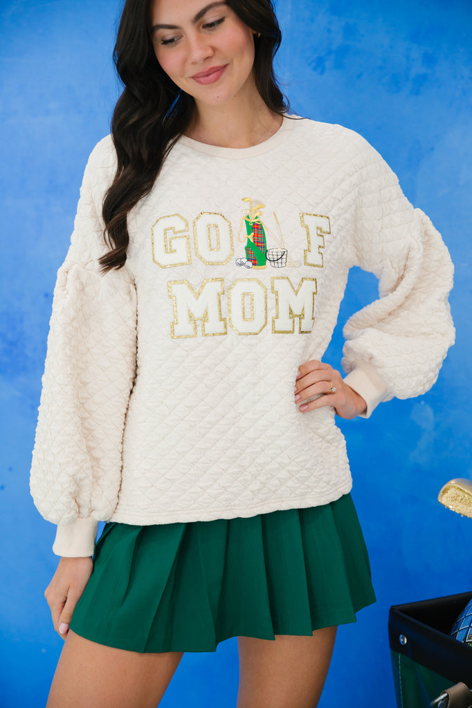 White quilted pullover with "golf mom" in white glam lettering and a golf patch. 