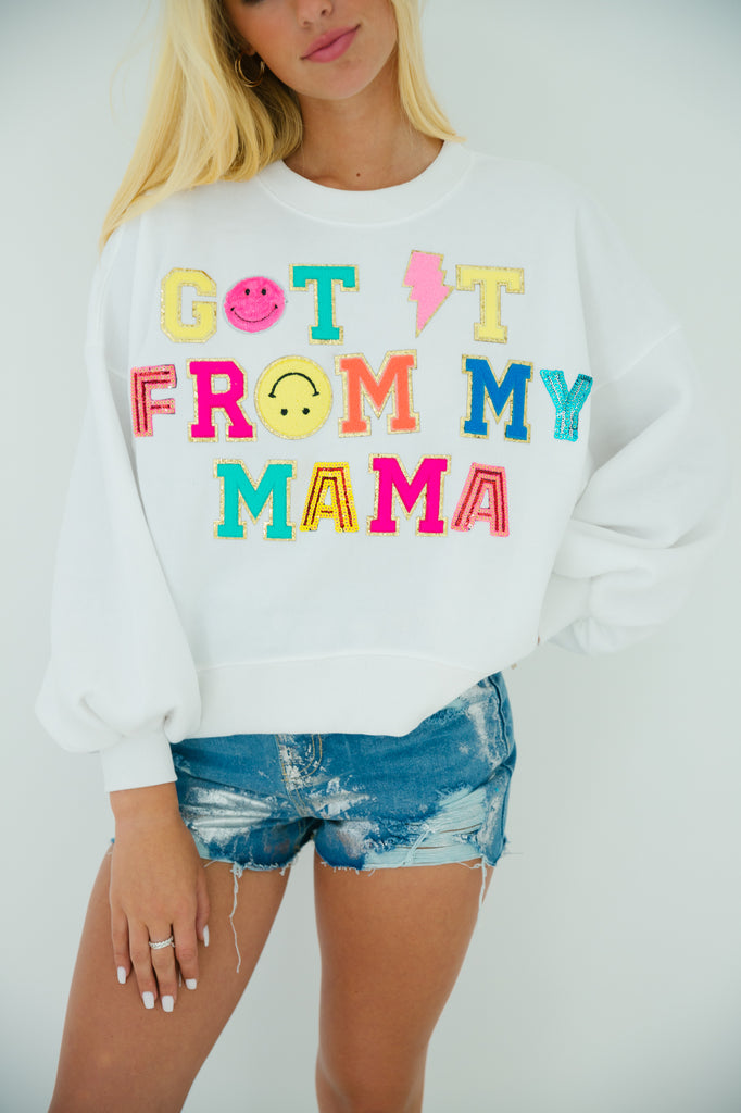White cropped pullover with "got it from my mama" in colorful terry and sequin lettering with smiley face patch. 