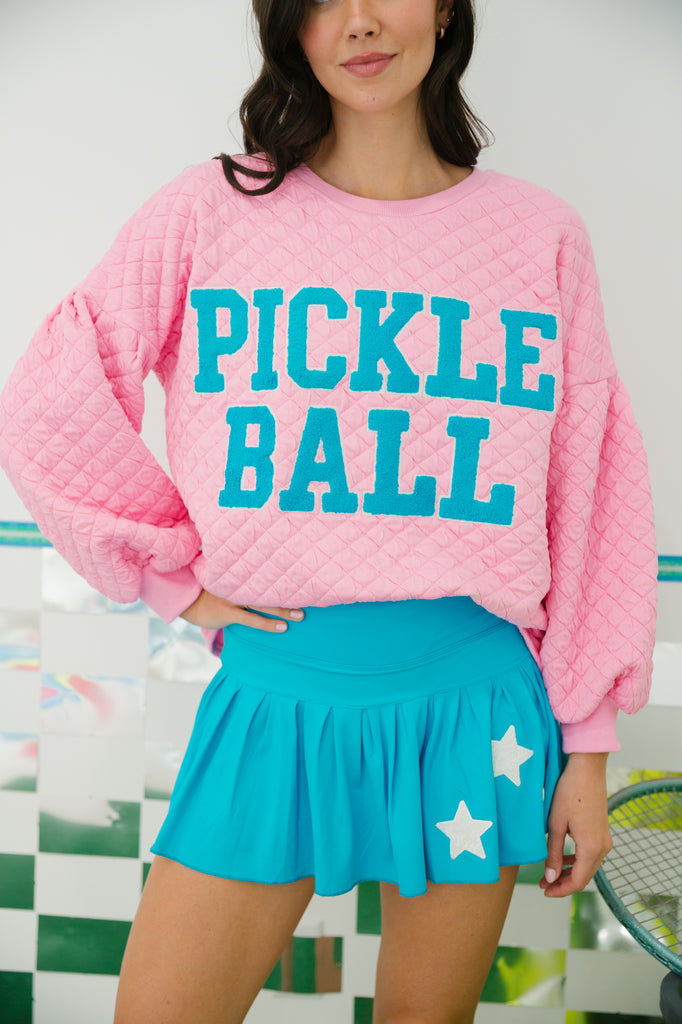Pink quilted pullover with "pickle ball" in blue varsity lettering. 