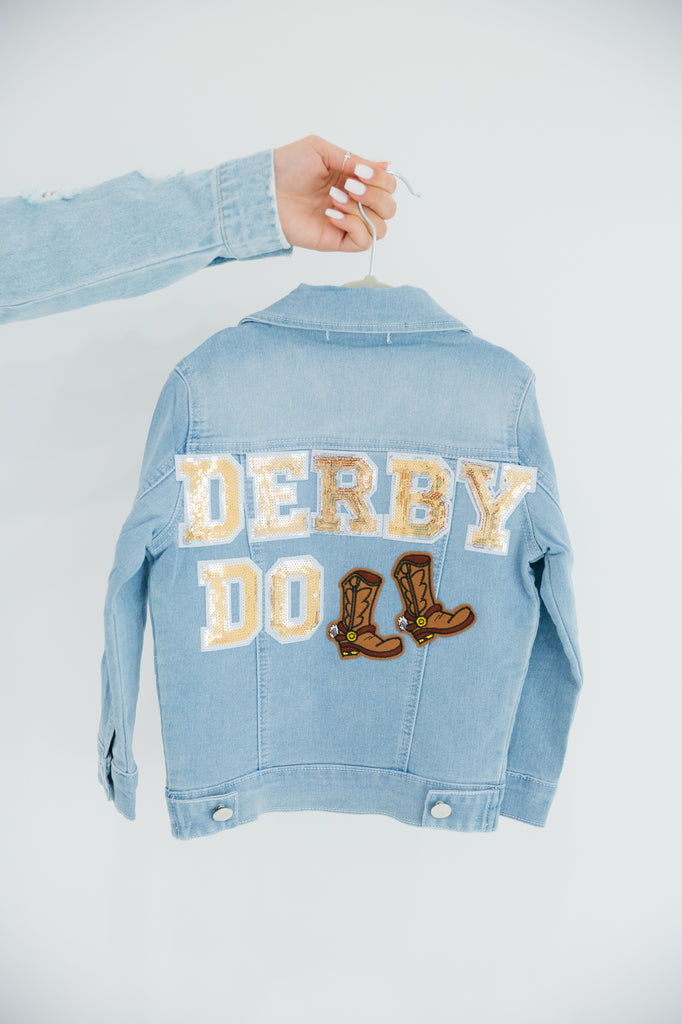 Kids denim jacket with "derby doll" in gold sequin lettering and cowboy boot patches. 