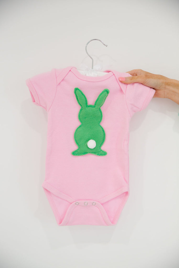 Light pink onesie with green bunny rabbit patch. 