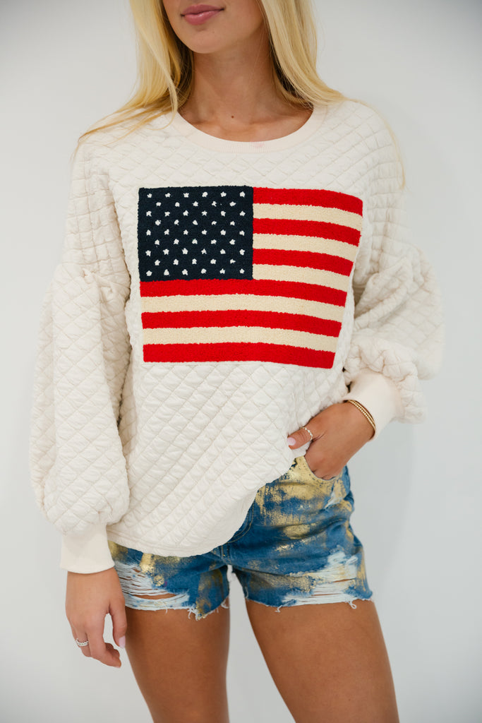 Cream quilted pullover with an American flag