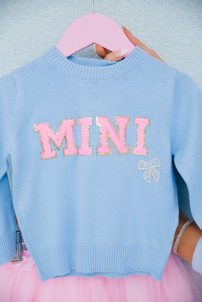 Light blue pullover with "mini" in mini pink terry lettering and a beaded bow patch. 
