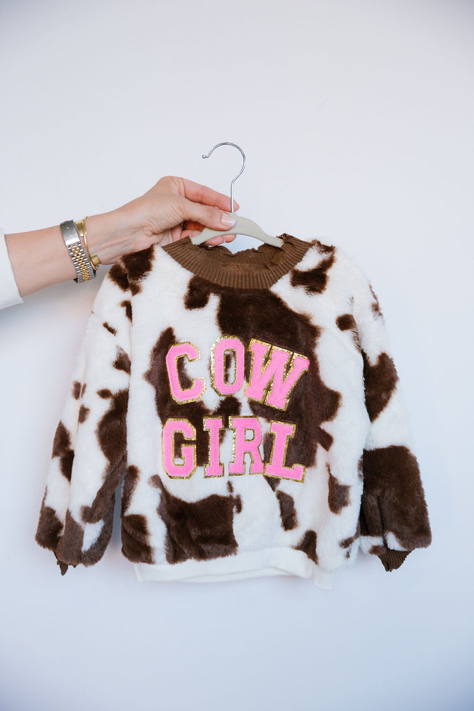 Kids cow print sherpa pullover with "cow girl" in pink terry letters. 
