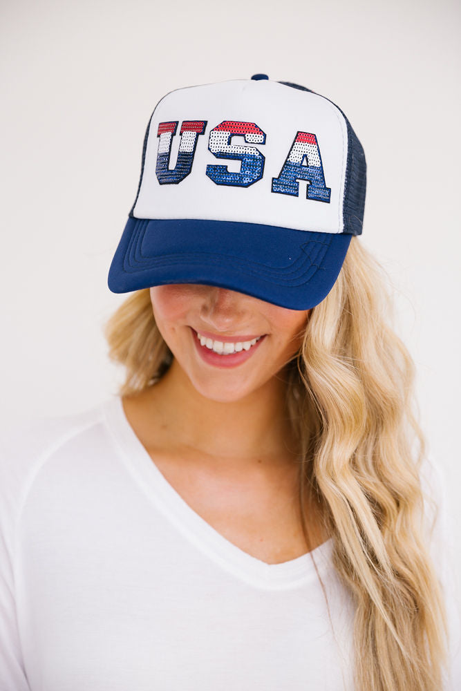 Navy and white trucker hat with red, white, and blue striped "USA" letters