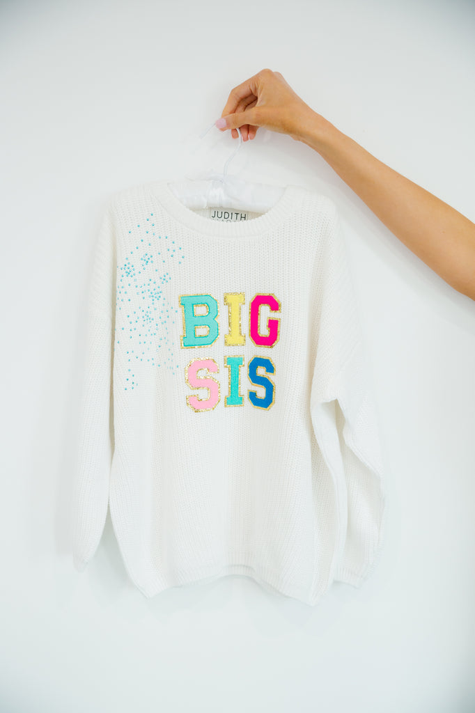 Kids white sweater with "big sis" in colorful terry lettering and blue rhinestone spray. 