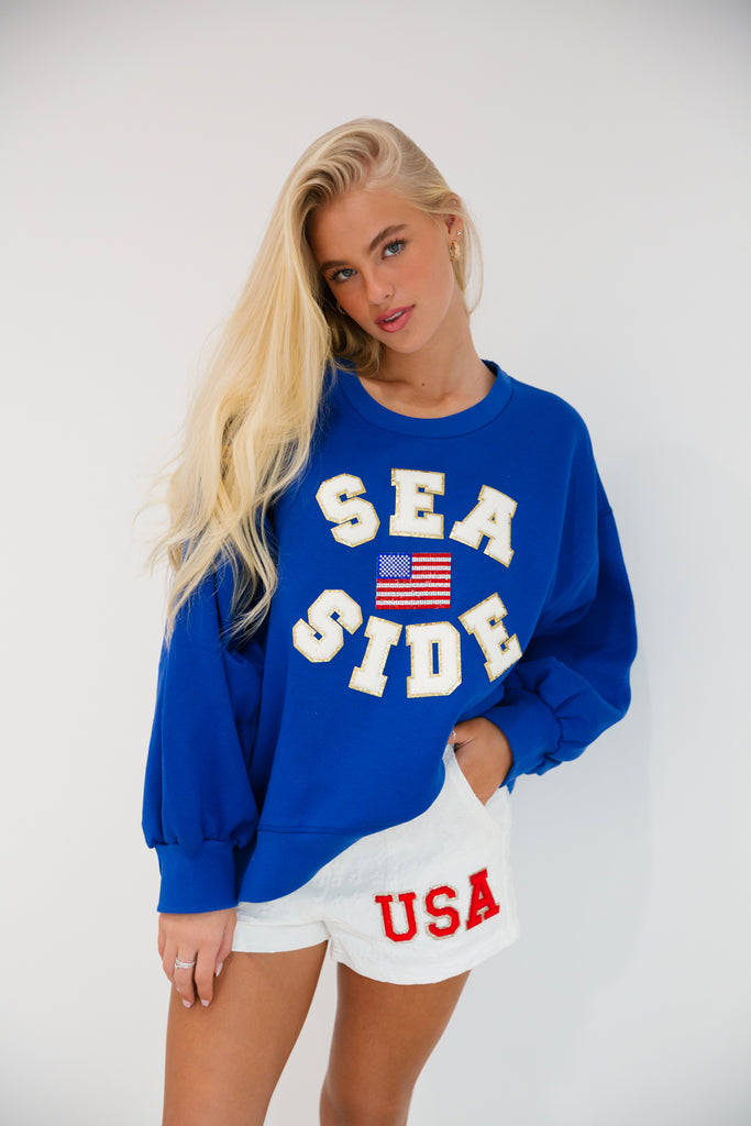 Royal blue cropped pullover in "Sea Side" in white letters and American flag patch
