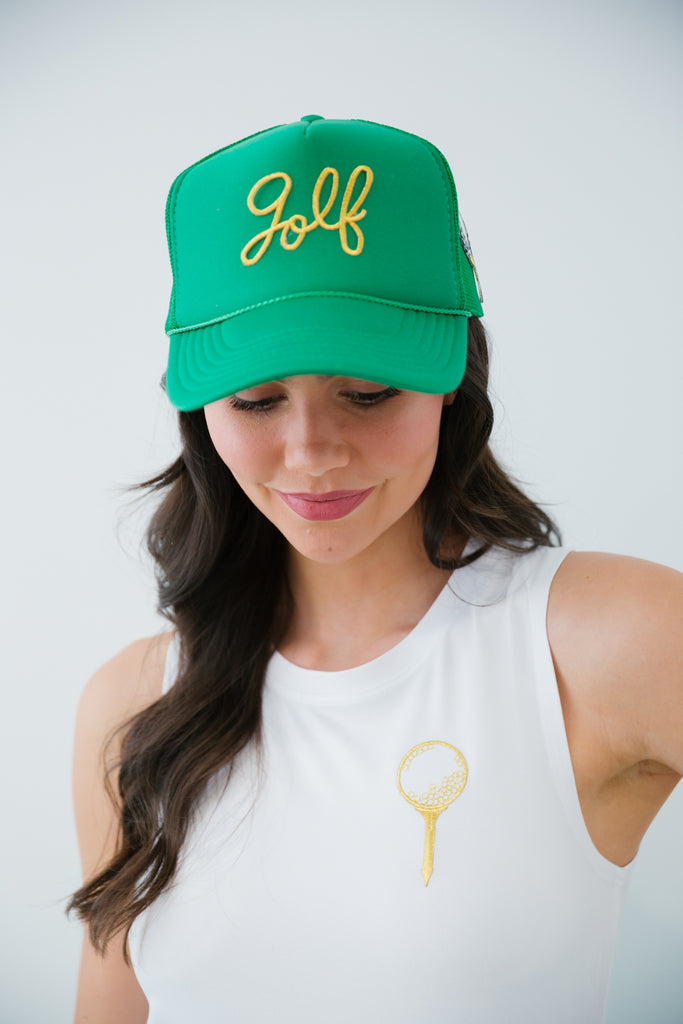 Green trucker hat with gold cursive golf patch and a golf tee patch on the side